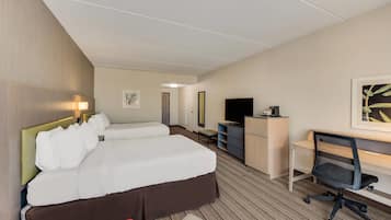 A hotel room with two beds, a desk, a chair, a TV, and a bookshelf.
