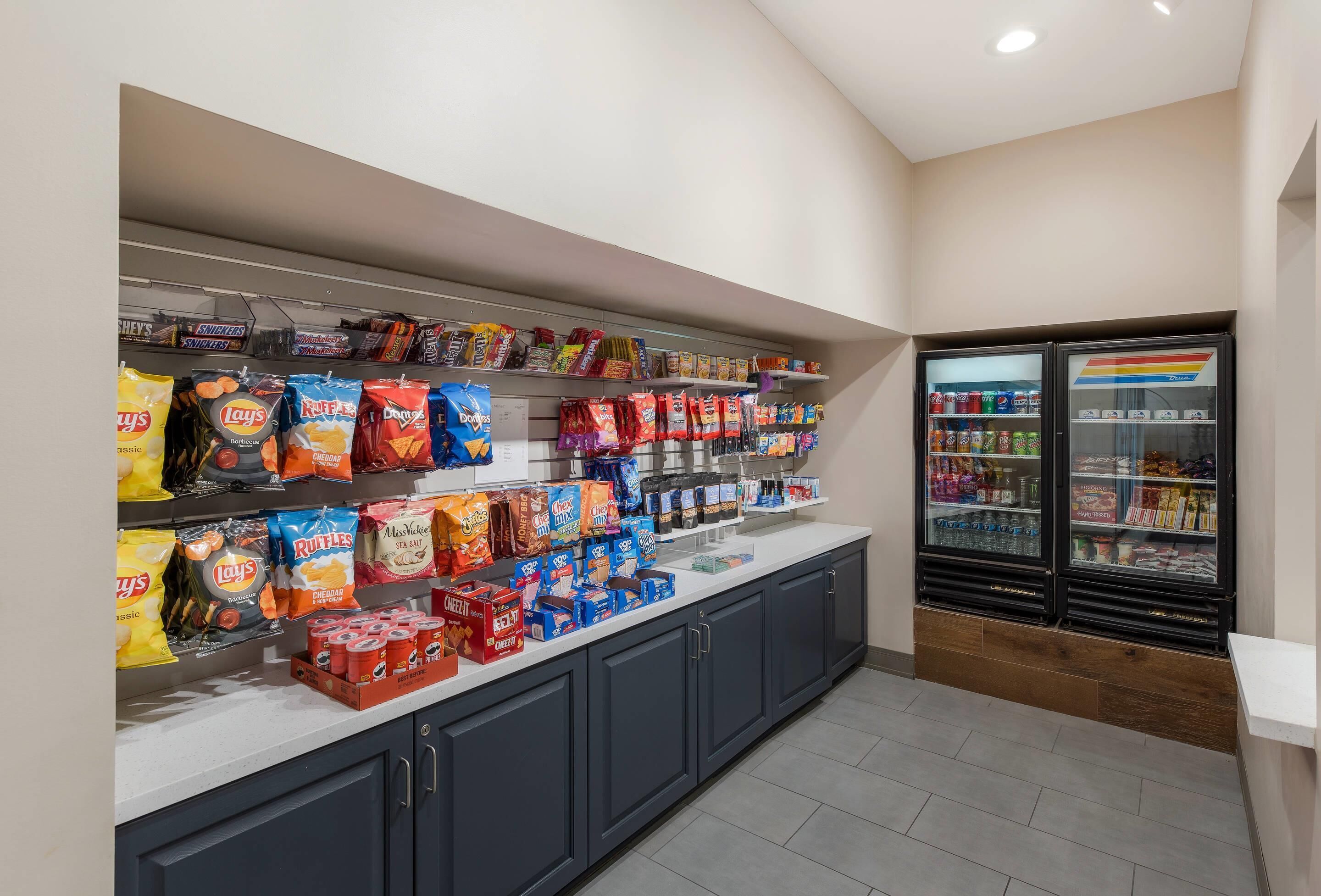 A snack bar with various chips and snacks, a refrigerated drink cooler, and a counter with beverages.