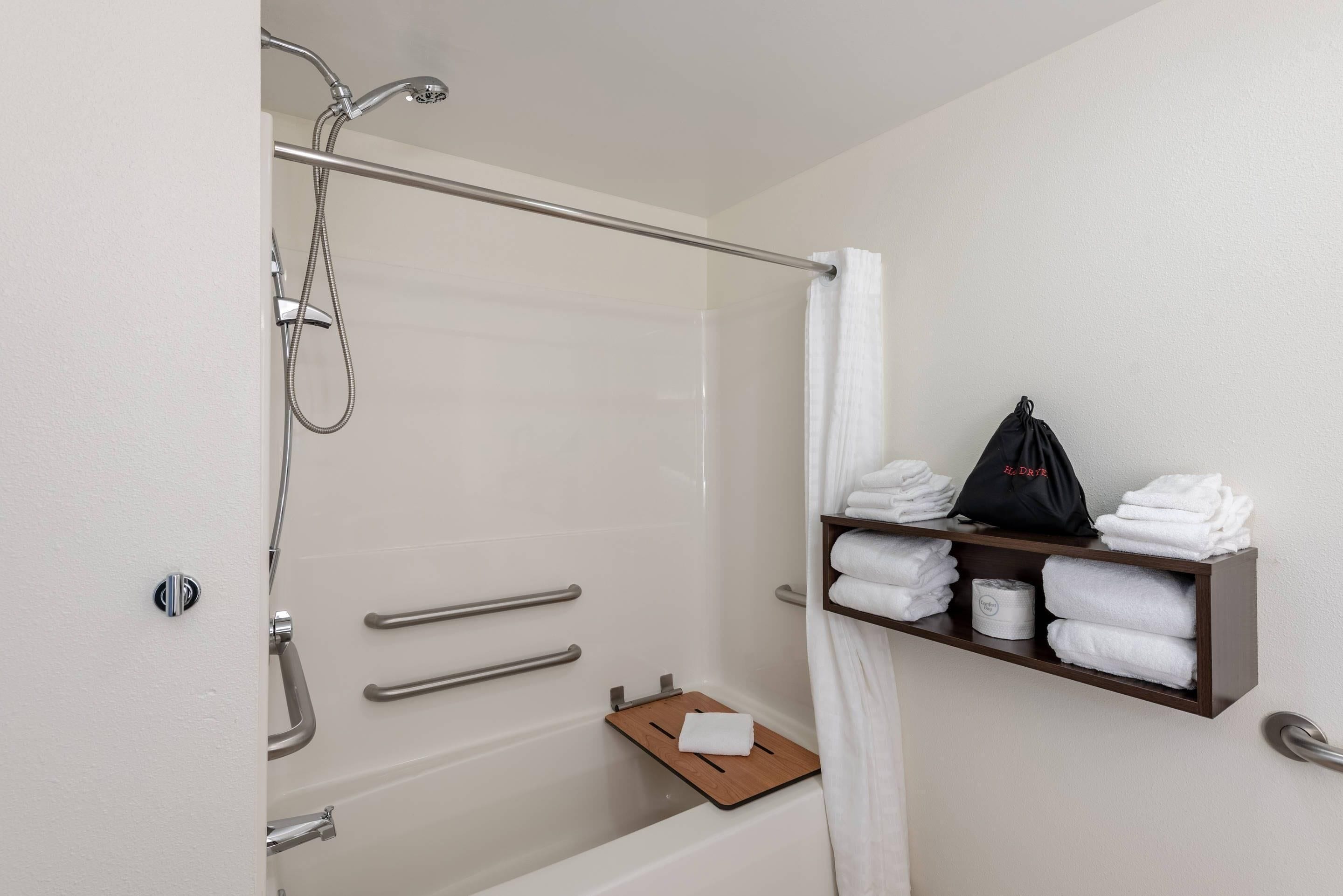 A bathroom with a bathtub, a shower, a towel rack, and a shelf with towels and toiletries.