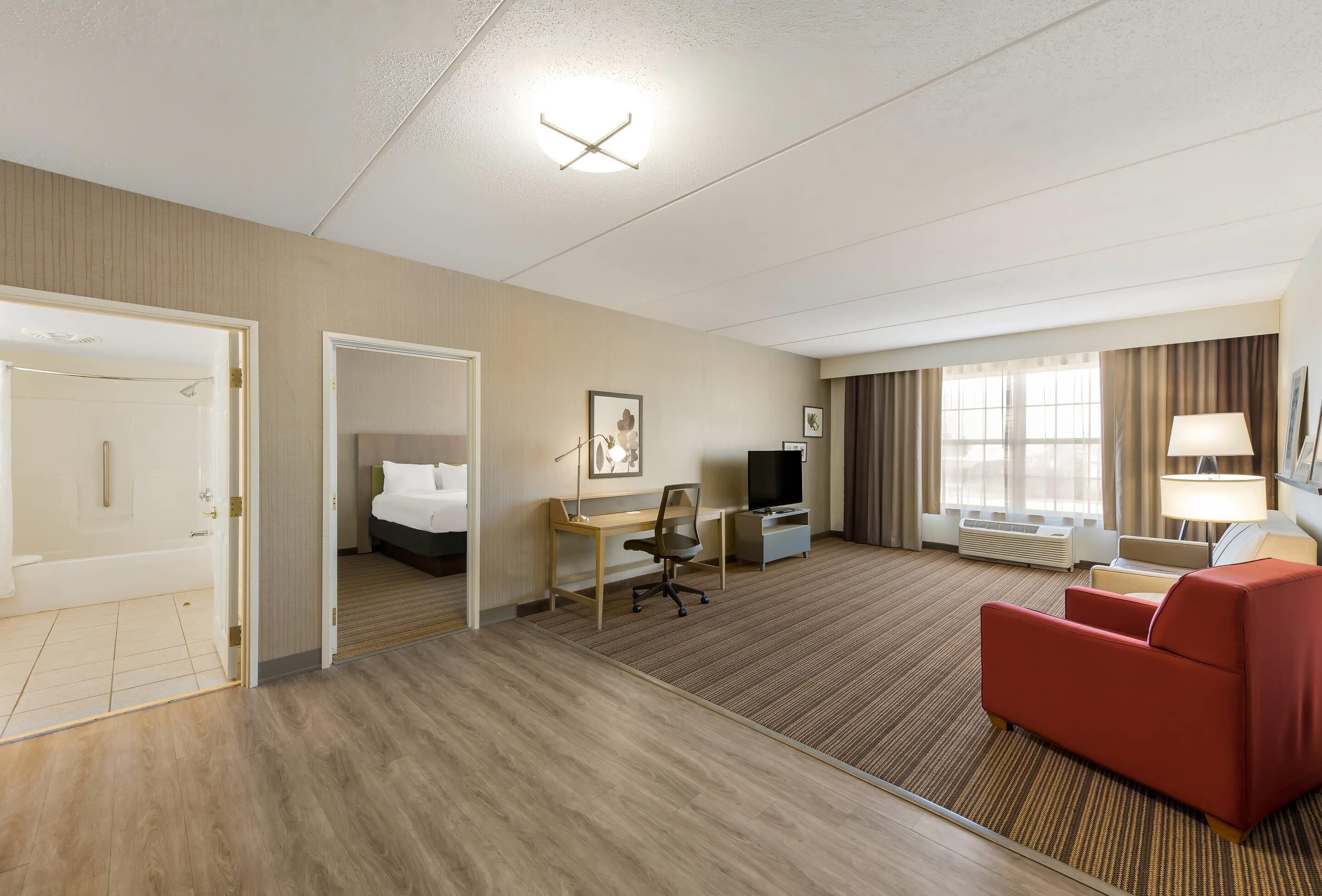 Una habitación de hotel con cama, escritorio, televisor y un sofá rojo.
