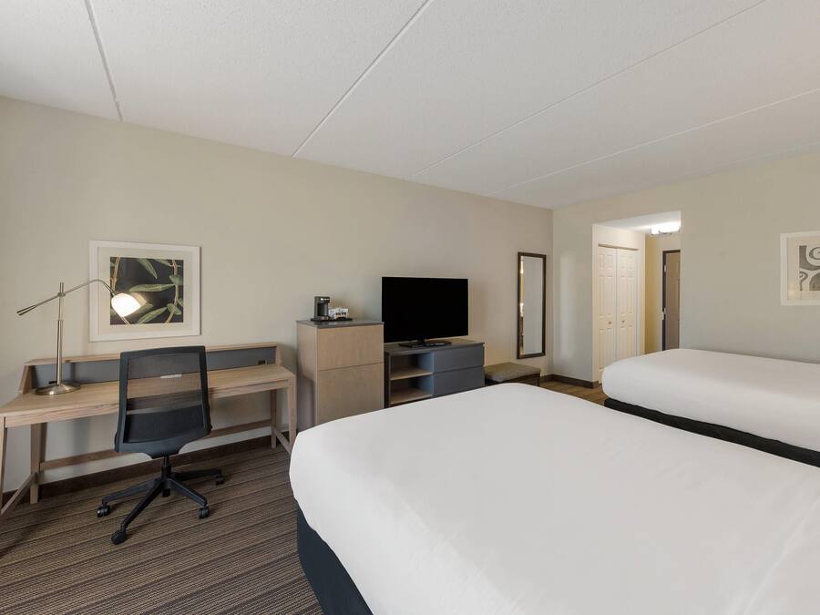 Habitació d'hotel amb un llit, un escriptori amb una cadira, una televisió i un mirall.