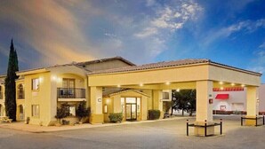 Un hotel con fachada amarilla, un acceso cubierto y un toldo rojo.