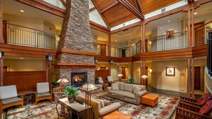 A spacious lobby with a high ceiling, a fireplace, multiple seating areas, and a decorative floor pattern.