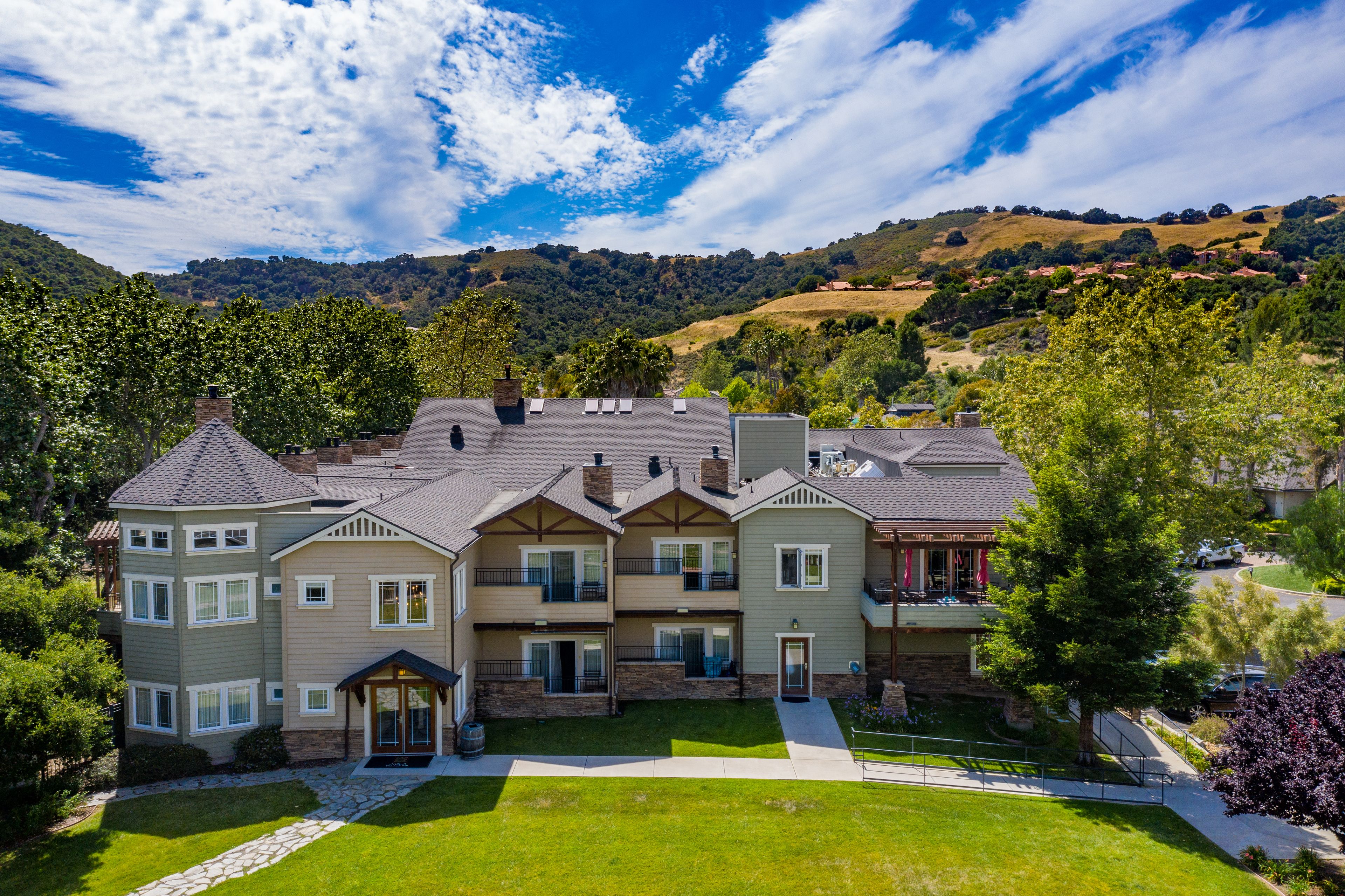 A multi-story residential building with a well-maintained lawn and a stone pathway leading to the entrance.