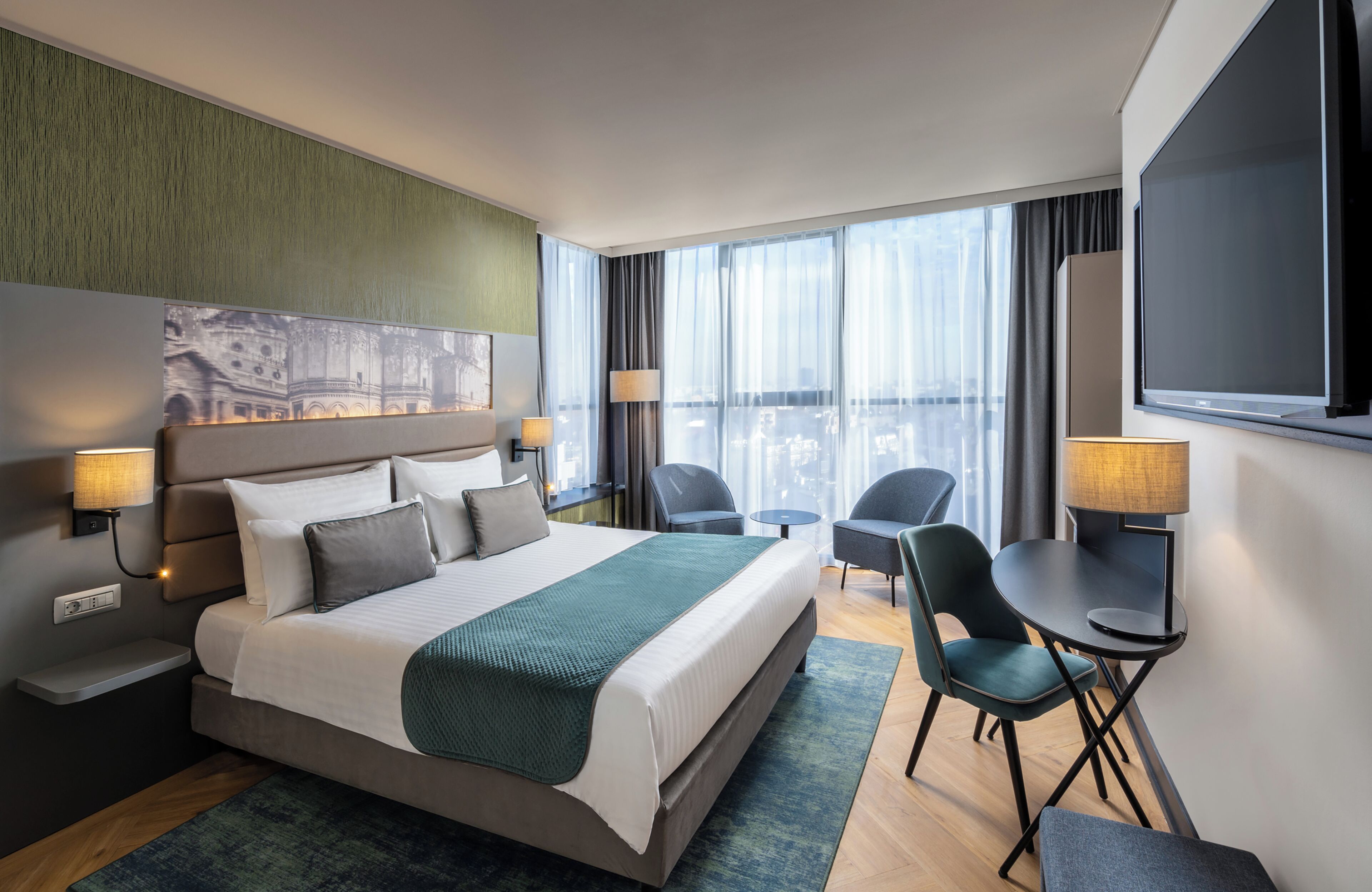 Une chambre d’hôtel avec un grand lit, un bureau, deux chaises, une télévision et une vue sur la ville.