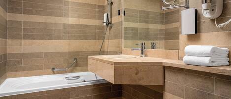 A modern bathroom with a bathtub, a sink, a mirror, and a towel rack.