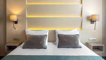 Habitación de hotel con una cama grande, dos lámparas de noche y un panel de control en la mesita de noche.