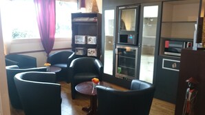 A compact living space with a kitchenette, a seating area with two chairs and a small table, and a bookshelf. - Hotel Kyriad Beauvais Sud (Beauvais)