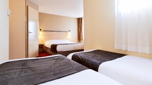 A hotel room with two beds, a bedside table, a lamp, and a window with curtains. - Hotel Kyriad Beauvais Sud (Beauvais)