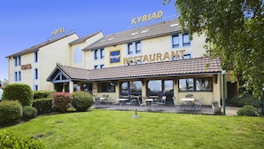 A hotel and restaurant with outdoor seating, a well-maintained lawn, and clear signage. - Hotel Kyriad Beauvais Sud (Beauvais)
