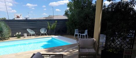 Un área de piscina con mobiliario de mimbre y una mesa.