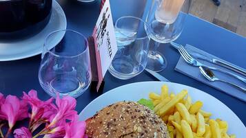 Ein Tisch mit einem Burger, Pommes, einer Wasserflasche und einer Suppenschüssel.