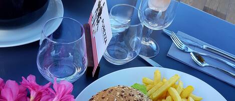 A table with a burger, fries, a bottle of water, and a bowl of soup.