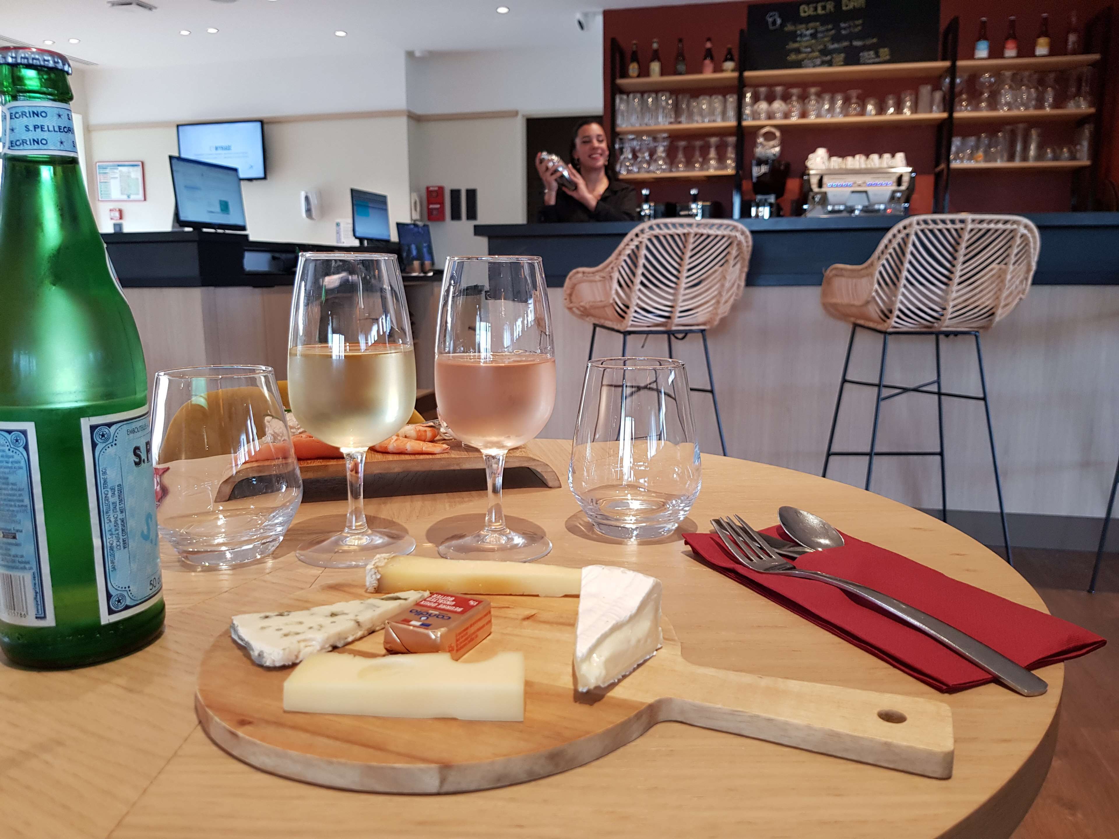 Een tafel met een fles, glazen, kaas en een mes.
