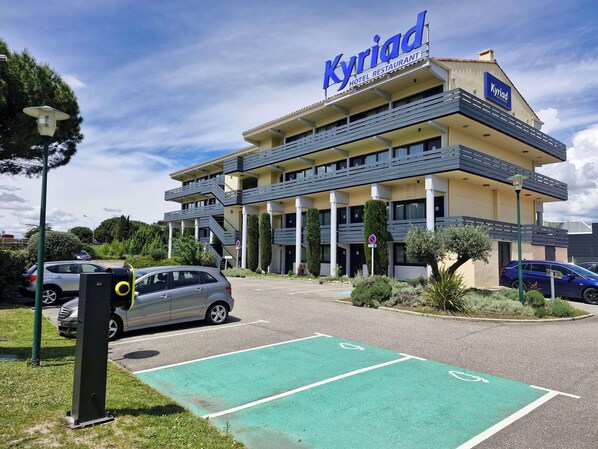 A hotel named 'Kyriad' with a modern design, multiple floors, and a parking area with designated spaces. - Kyriad Carcassonne - Aéroport (Carcassonne)