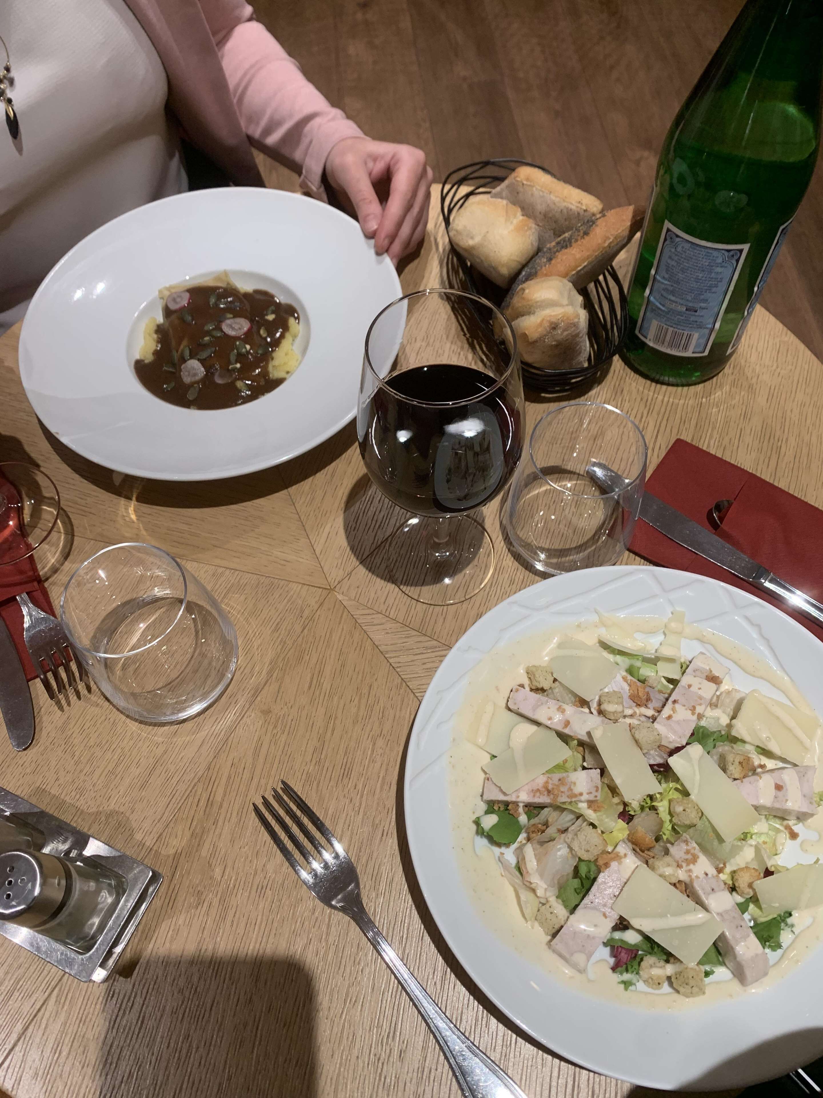 Una mesa de comedor con platos de comida, copas de vino y cubiertos.