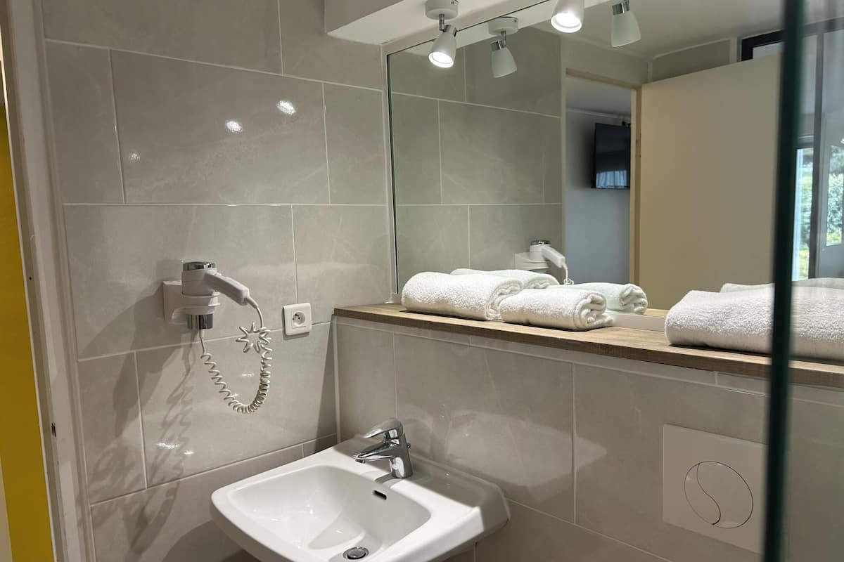 Un baño moderno con lavamanos, espejo y perchero para toallas.