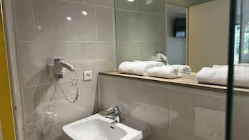 A modern bathroom with a sink, mirror, and towel rack.