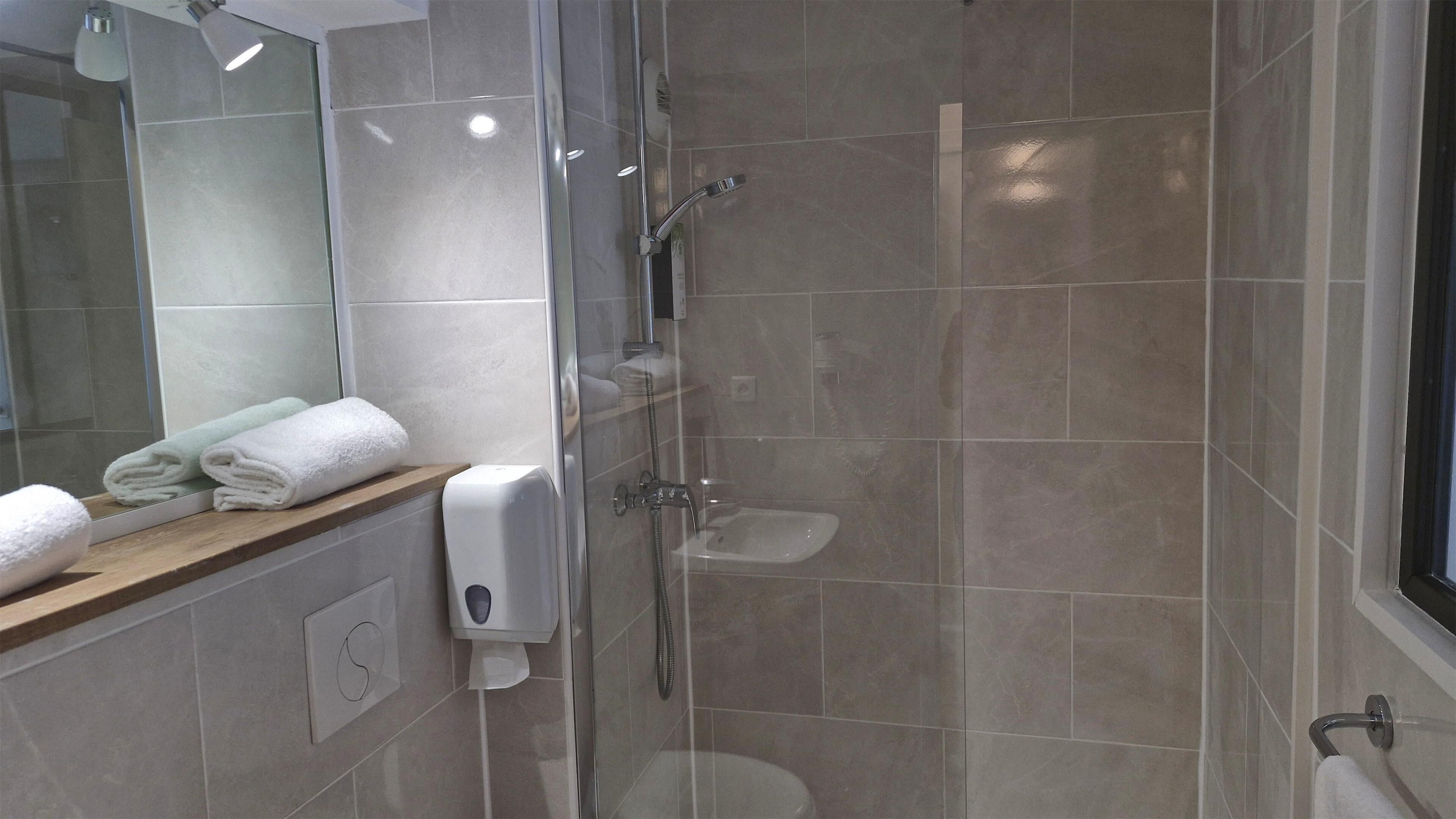 Un baño moderno con ducha de vidrio, inodoro y lavamanos.