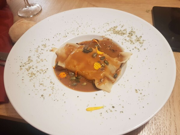 A plate of ravioli with sauce and garnishes on a white plate.