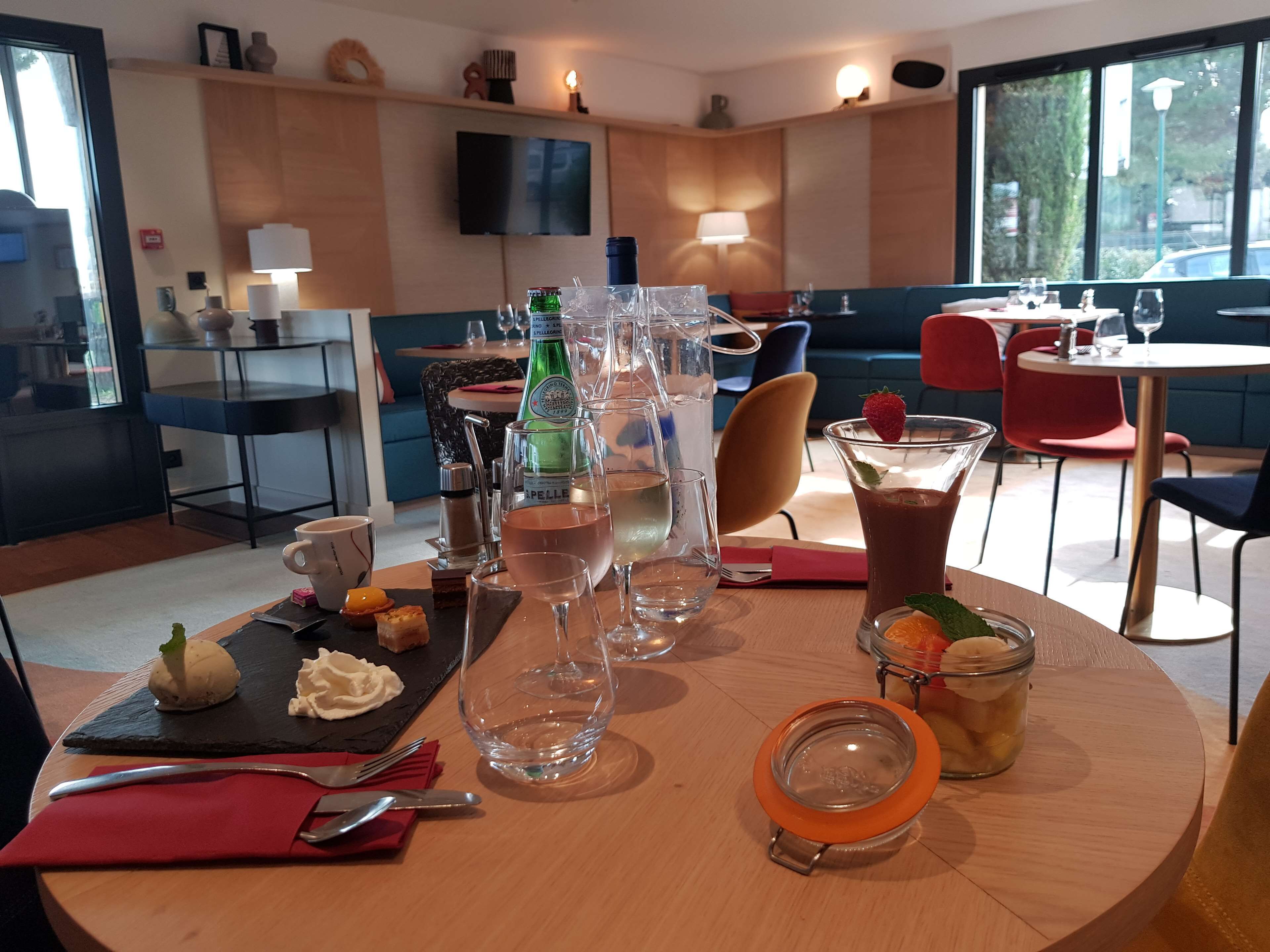 A dining area with a round table set for two, featuring a variety of drinks and a dessert.