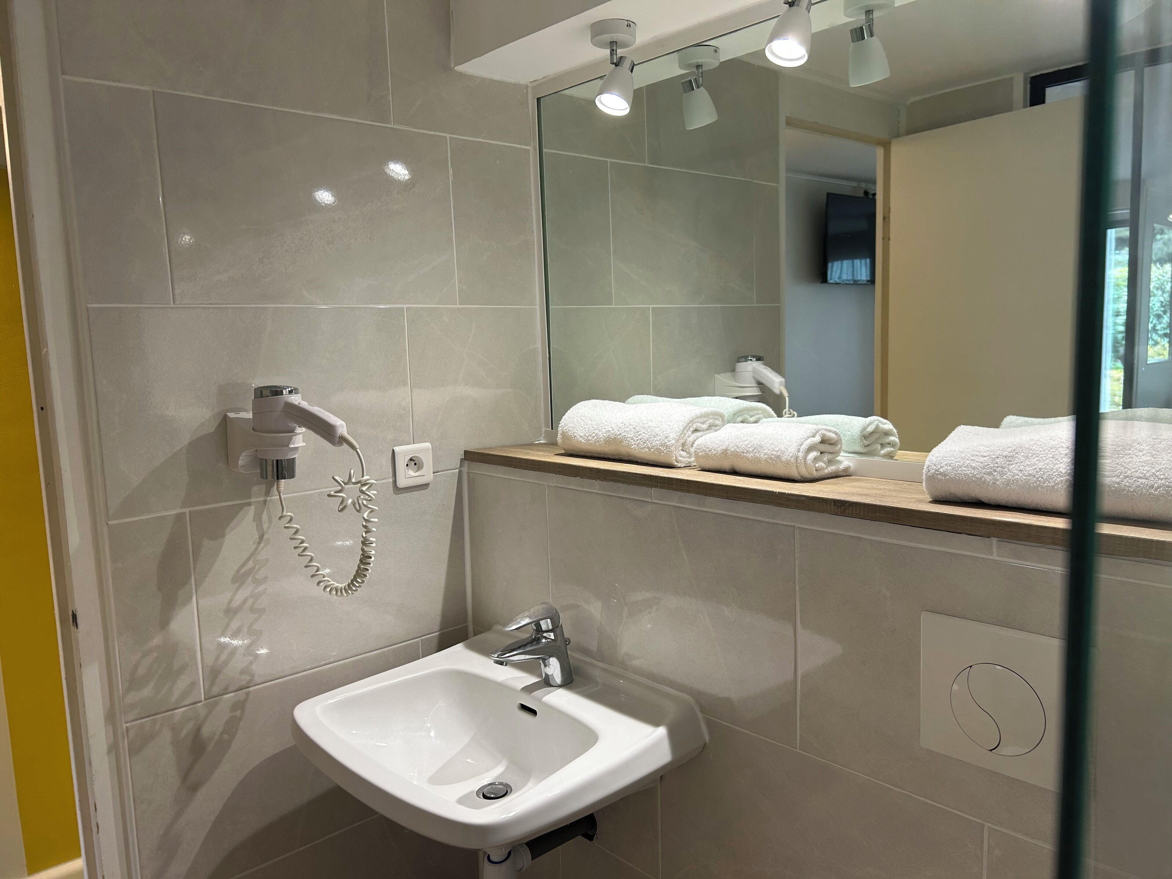 Uma casa de banho moderna com lavatório, espelho e suporte para toalhas.