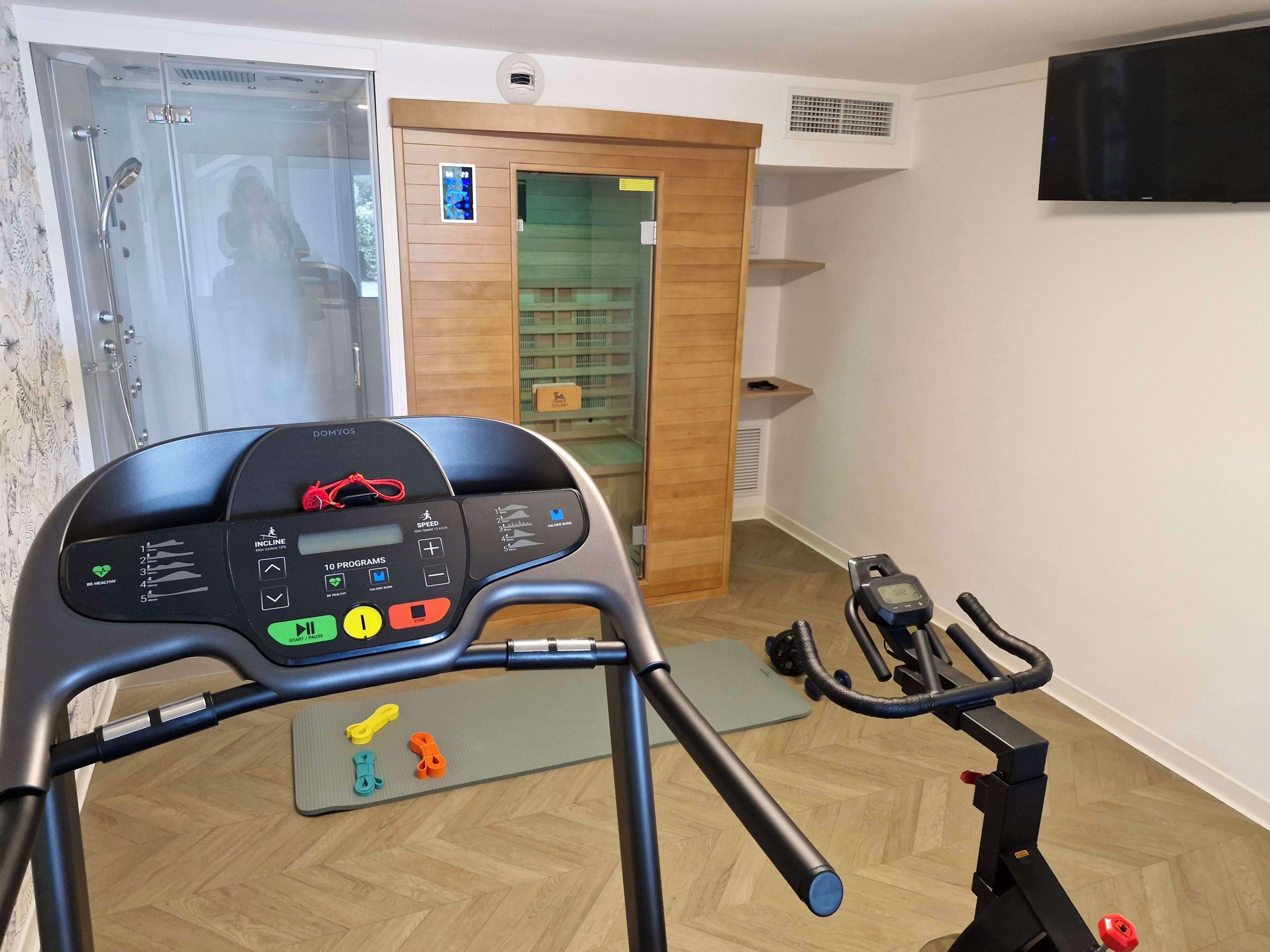 A home gym with a stationary bike, a treadmill, and a weight bench.