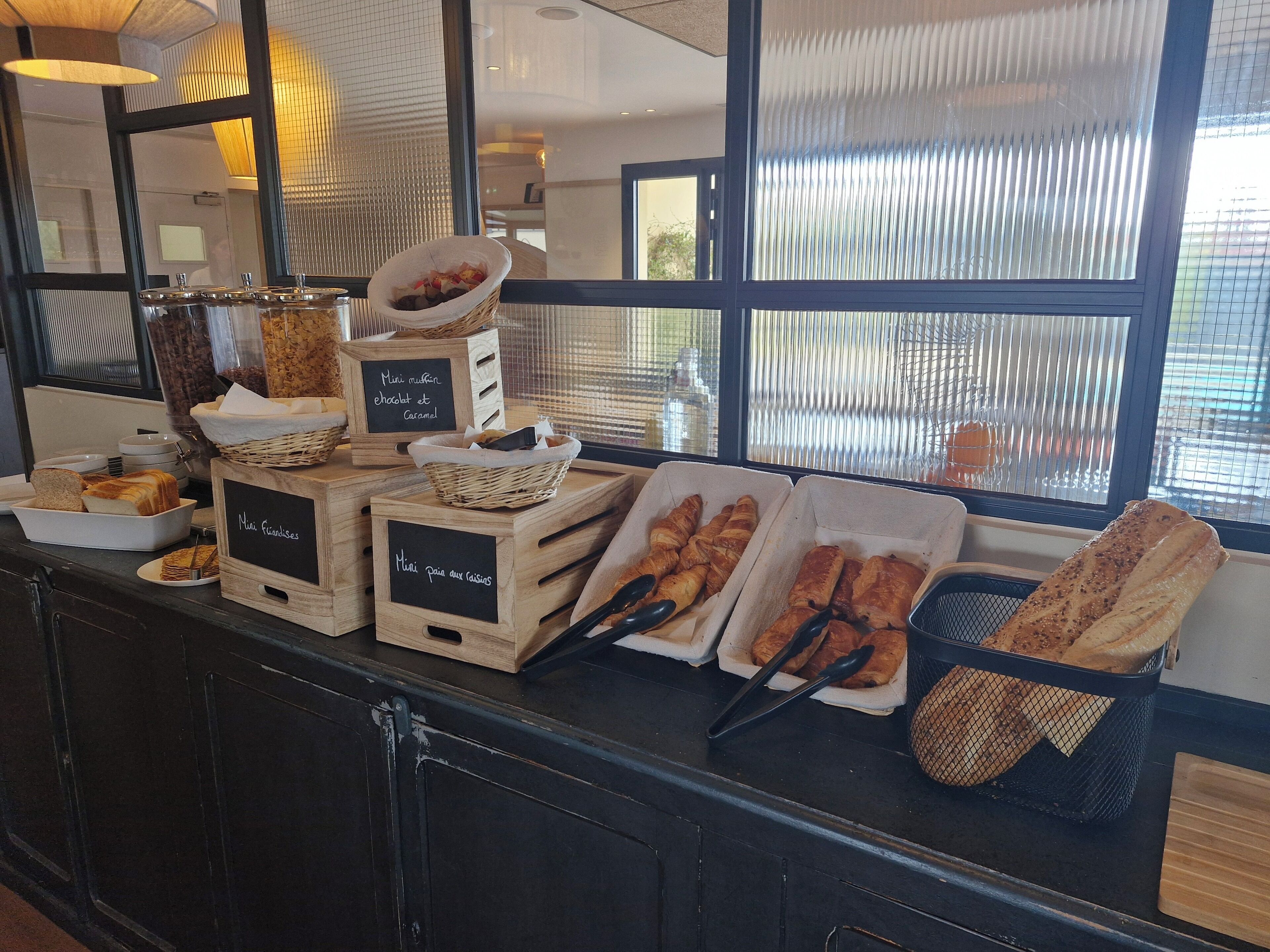 Un bufé de desayuno con diversos pasteles y pan, expuestos en cestas y bandejas.