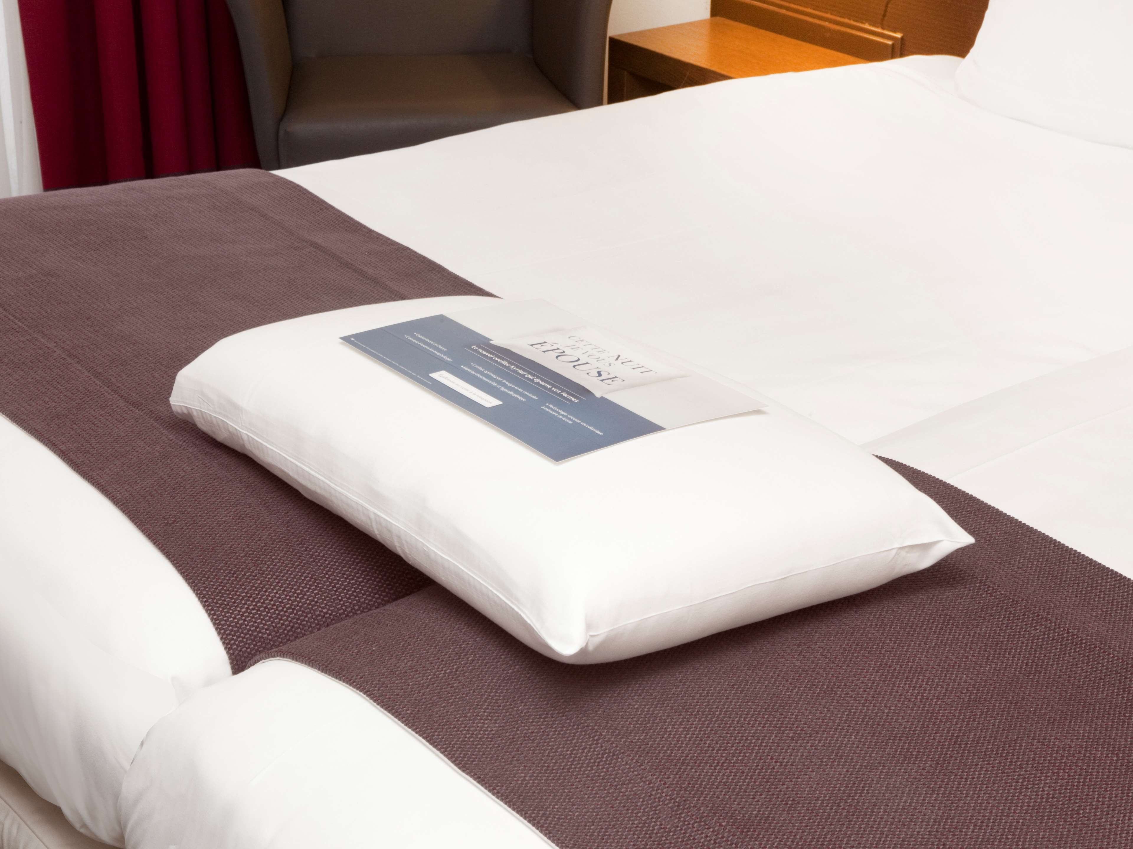 Een net opgemaakt bed met een kussen en een label erop.