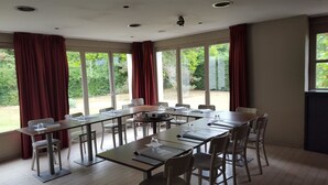 A conference room with a long table, chairs, and a projector. Large windows with curtains are visible. - Kyriad Chantilly (Gouvieux)