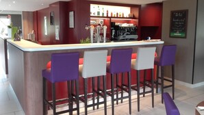 Un área de bar moderna con mostrador, taburetes y una máquina de café.