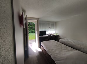 A hotel room with a bed, a desk with a computer, a chair, and a window with curtains. - Campanile Sable Sur Sarthe (Vion)