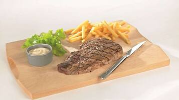 Ein Steak mit Pommes und einem gemischten Salat auf einer Holzplatte.