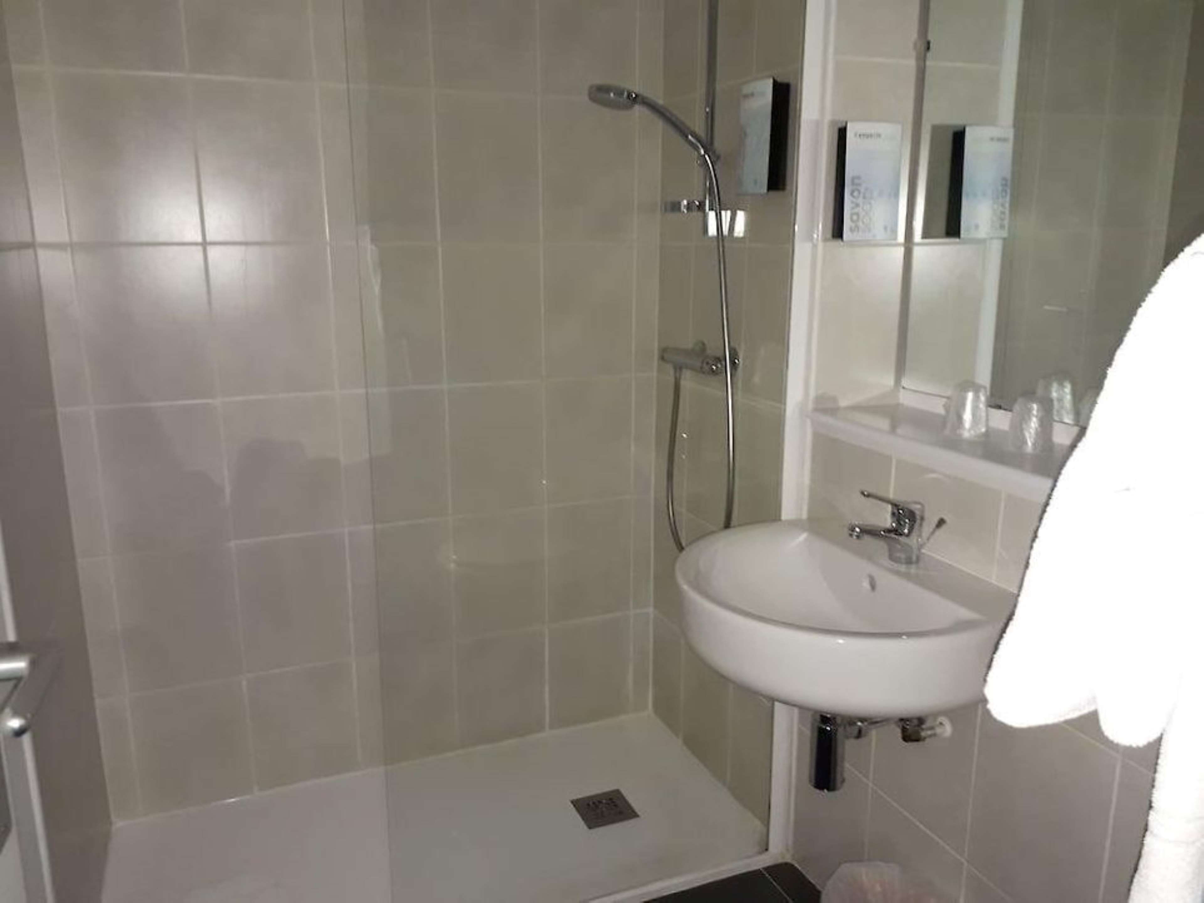 A bathroom with a shower, a sink, and a mirror.