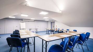 A conference room with a long table, blue chairs, and white walls.