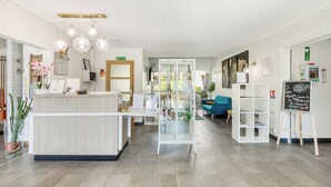 Un espace d’accueil comprenant un comptoir, un canapé bleu, une vitrine et un tableau noir servant de menu.