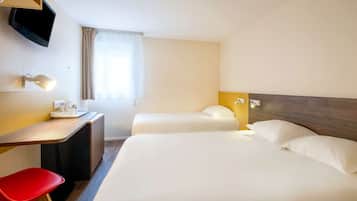 A hotel room with a bed, a desk, a chair, a TV, and a window with curtains.