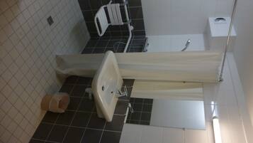 Een badkamer met een wit wastafel, toilet en douchegedeelte.