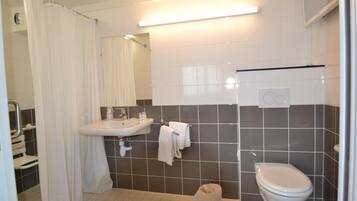 A bathroom with a sink, toilet, and shower curtain.