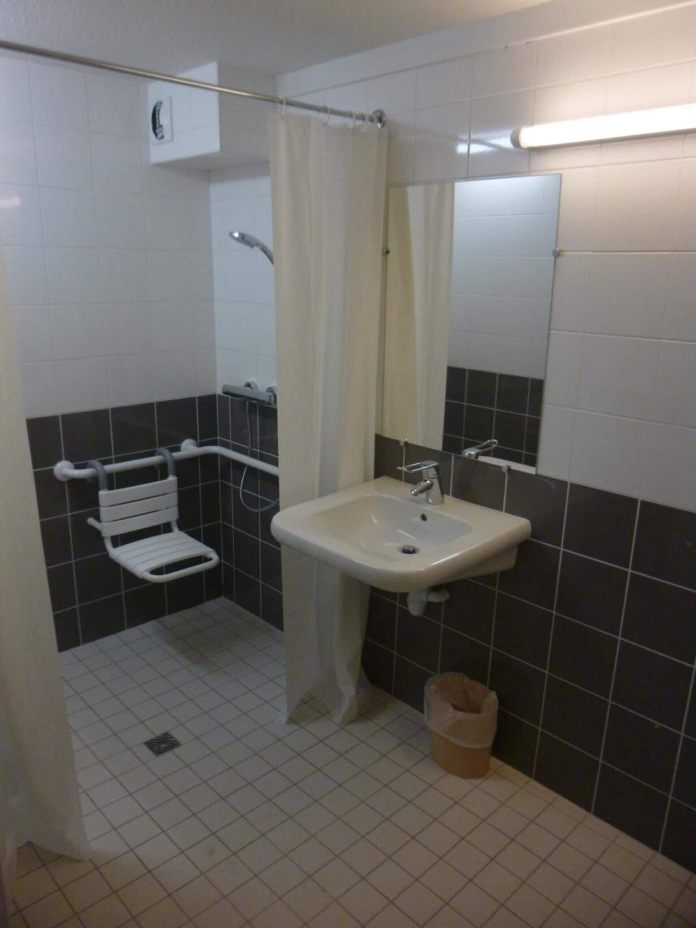 A small bathroom with a white sink, a mirror, a towel rack, and a shower curtain.