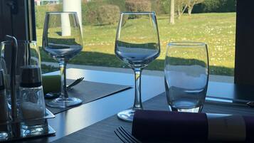 A dining table with three wine glasses, a salt and pepper shaker, and a fork on a dark placemat.