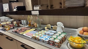 A buffet counter with various food items, including meats, cheeses, and dairy products. - The Originals Boutique, Hôtel Montélimar (Montélimar)