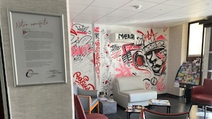 A modern hotel lobby with graffiti art on the walls, a framed certificate, and comfortable seating areas. - The Originals Boutique, Hôtel Montélimar (Montélimar)