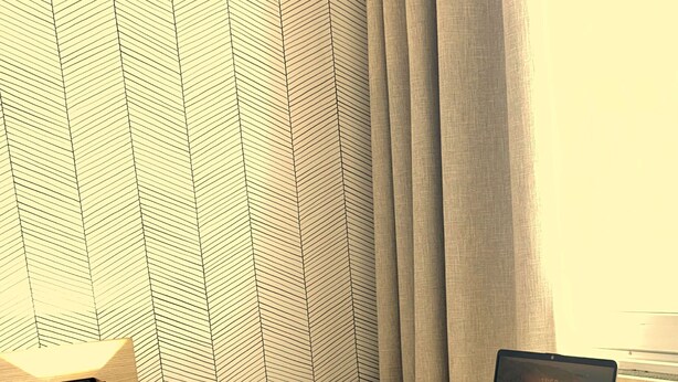 Un espacio de trabajo moderno con una computadora portátil sobre un escritorio, una silla verde y una pared con diseño geométrico.