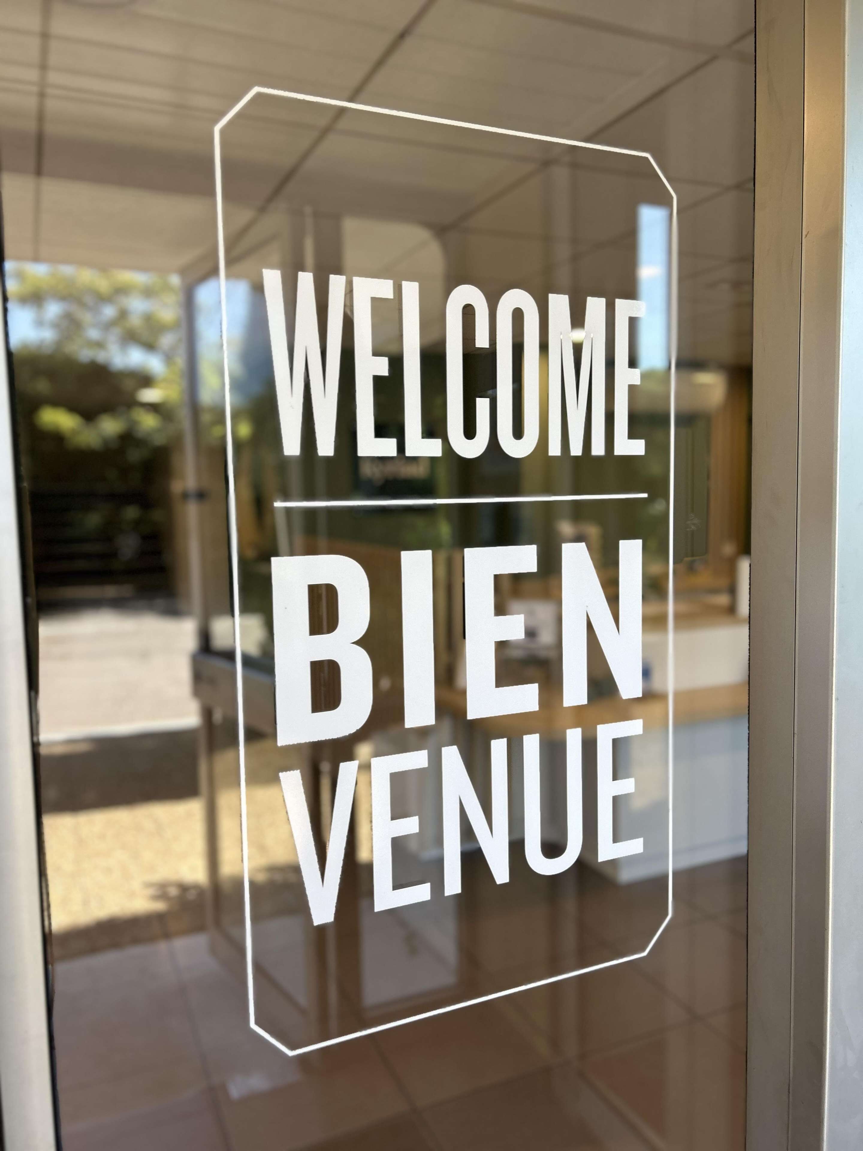 Eine Glastür mit der Aufschrift 'WELCOME BIENVENUE'.