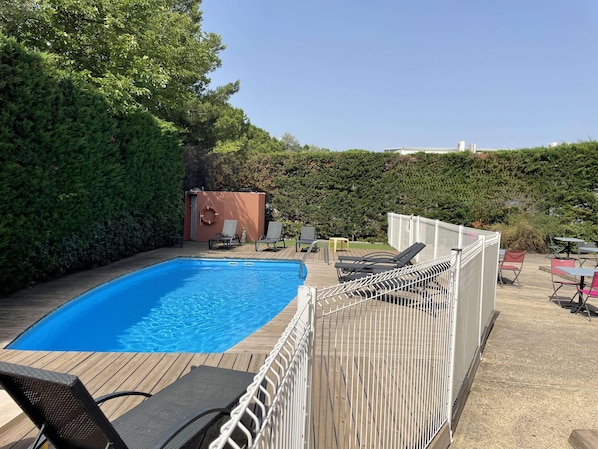 Een seizoensgebonden buitenzwembad en ligstoelen