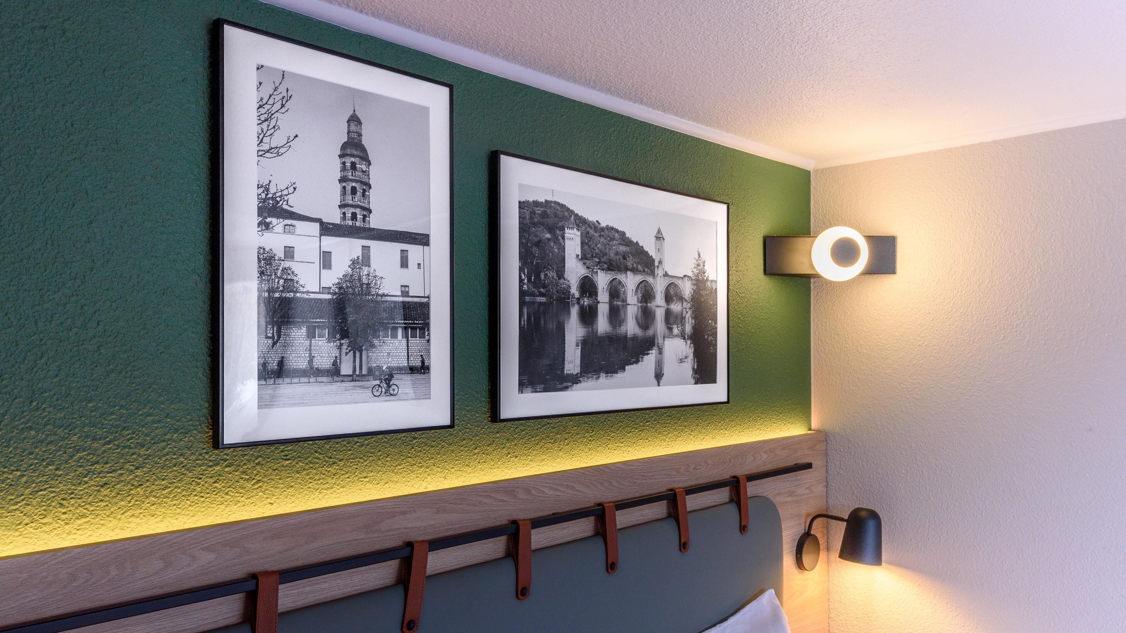 Two black and white photographs of buildings on a green wall.