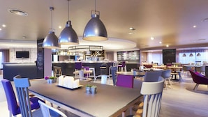 A modern hotel lobby with a bar area, seating arrangements, and a television mounted on the wall. - Campanile NATURE - Saint-Germain-en-Laye (Saint-Germain-en-Laye)