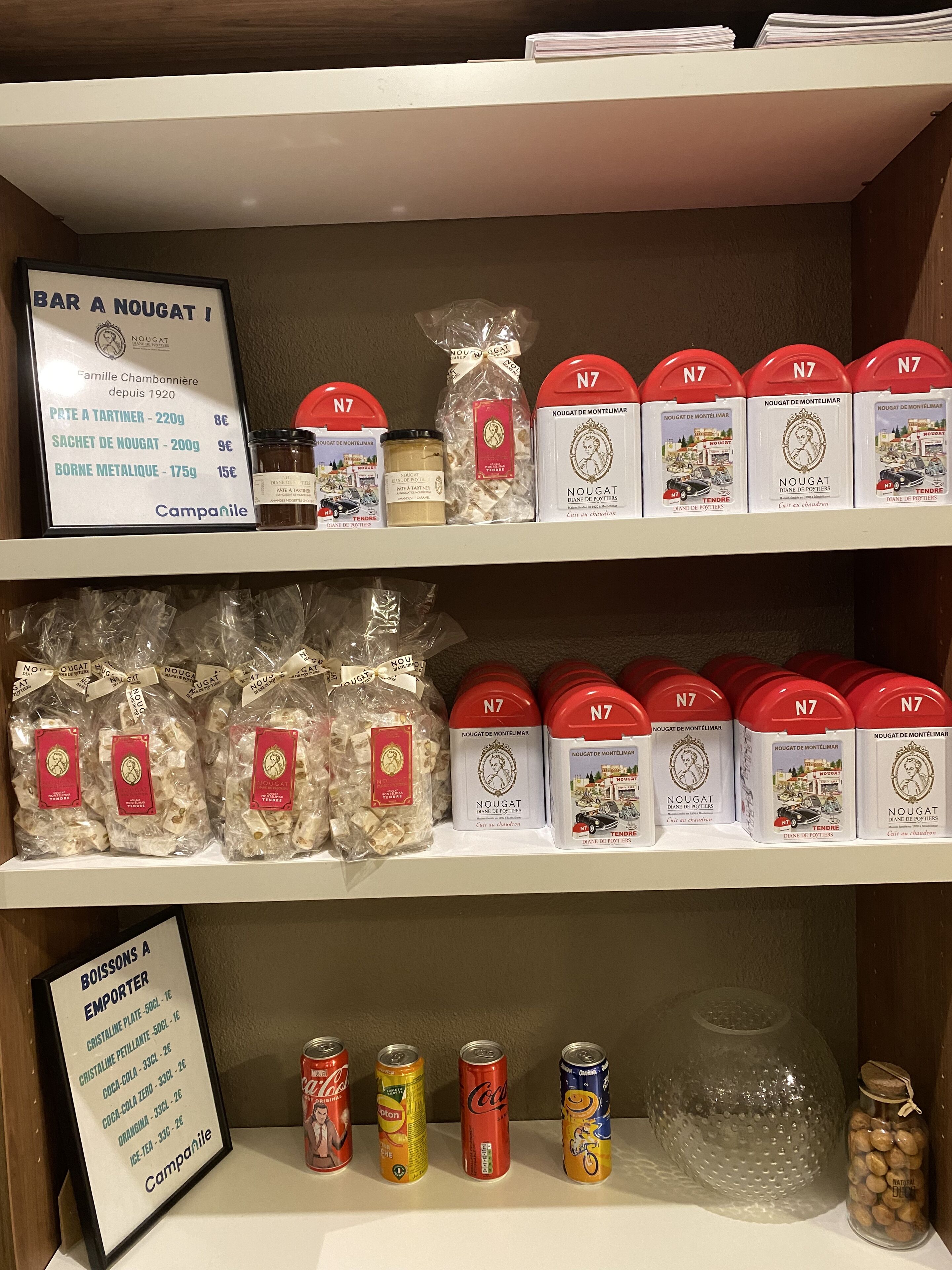 Estantes repletos de diversos productos alimenticios, incluyendo botes de nougat y aperitivos envasados.