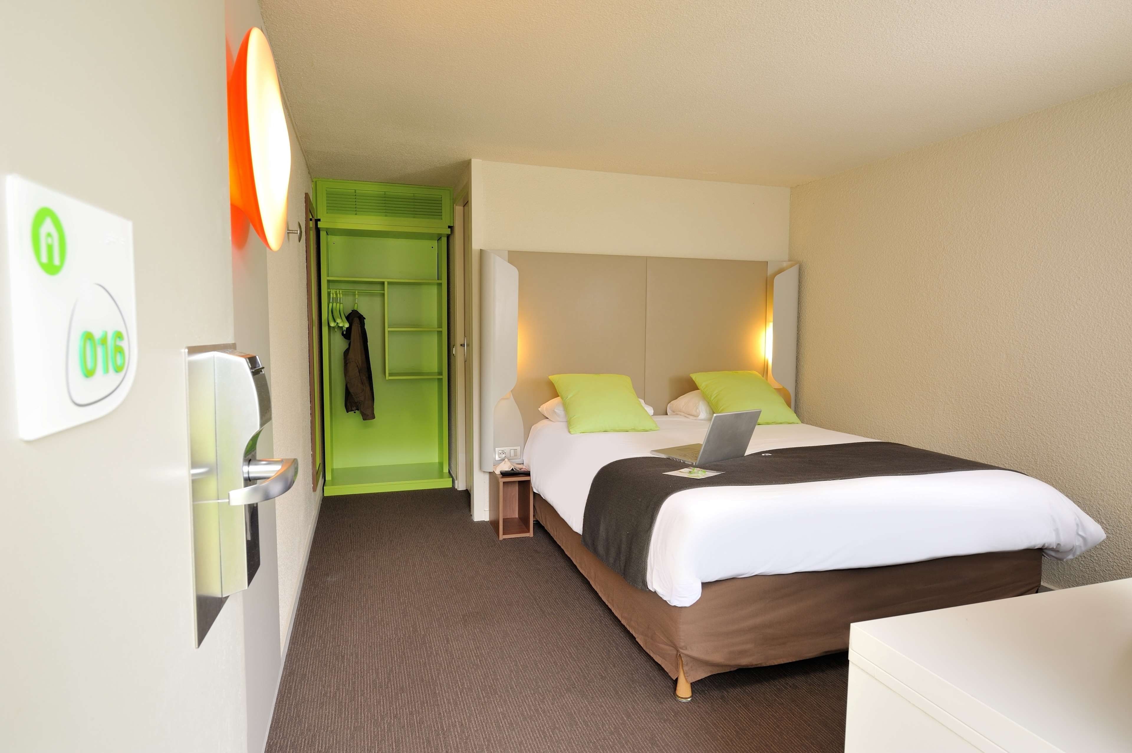 Una habitación de hotel con cama, escritorio, silla, armario y baño.
